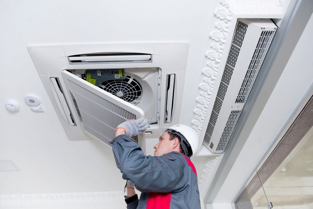 A Man is Working on a Ceiling Mounted Air Conditioner — Complete Airconditioning & Refrigeration in Darwin, NT
