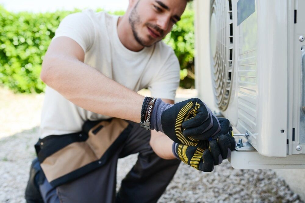 A Man is Working on an Air Conditioner Outside of a Building — Complete Airconditioning & Refrigeration in Darwin, NT