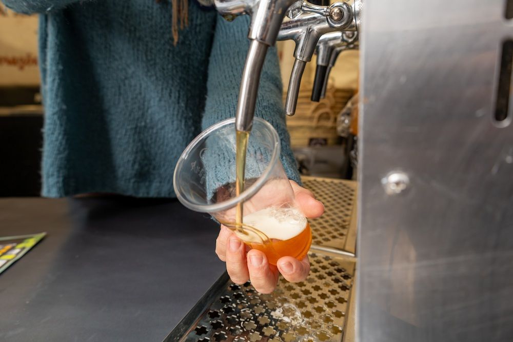 A Person is Pouring Beer Into a Glass From a Tap — Complete Airconditioning & Refrigeration in Darwin, NT
