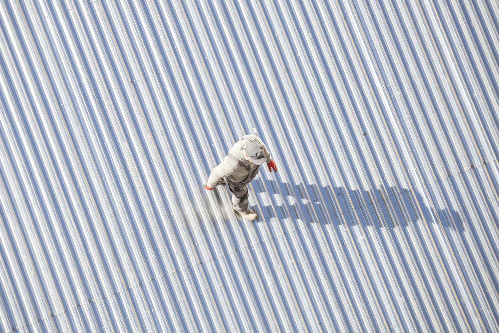 An Aerial View of a Person Standing on a Striped Roof — Wagga Roof Repairs In Gundagai, NSW