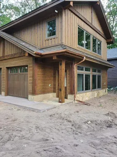 Two-story wood-sided house with copper gutters, multiple windows, and a garage. Building is under construction.
