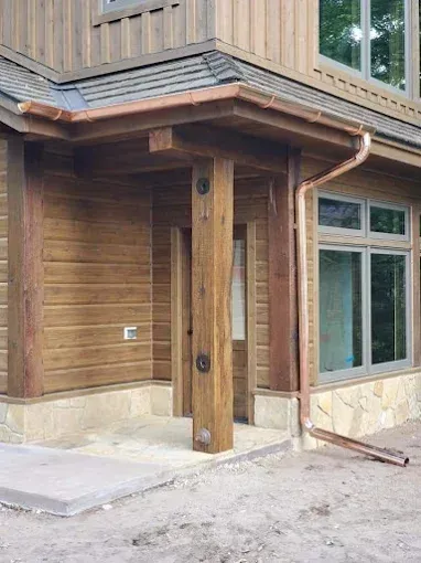 Wooden house exterior with copper gutters and porch posts.