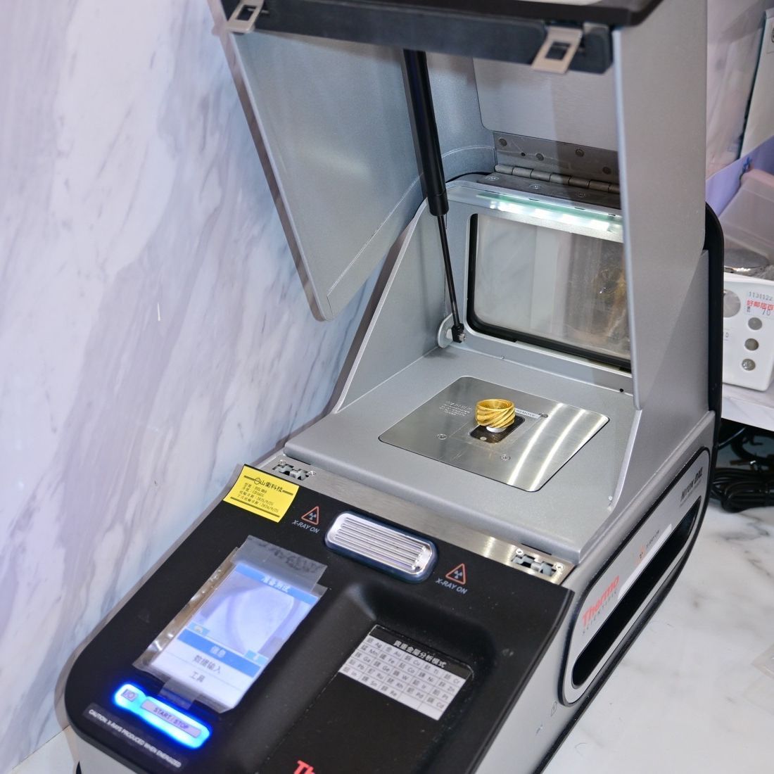 典金石以 Thermo Scientific 專業檢測儀，正在 X 螢光檢測黃金戒指