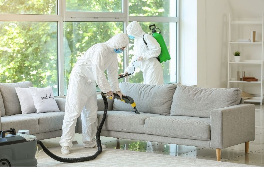 Professional biohazard cleanup technician in full protective equipment performing decontamination