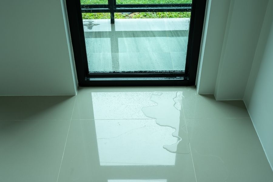 Rainwater pooling at a door threshold during a heavy Central Texas storm, showing how water intrudes into homes