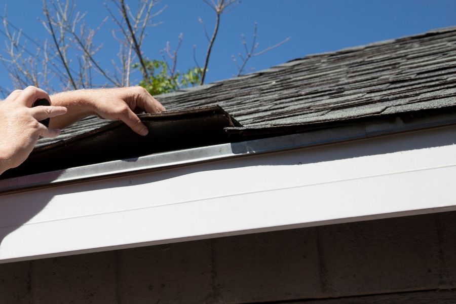 Roof inspection in progress, checking shingles and flashing for storm vulnerability