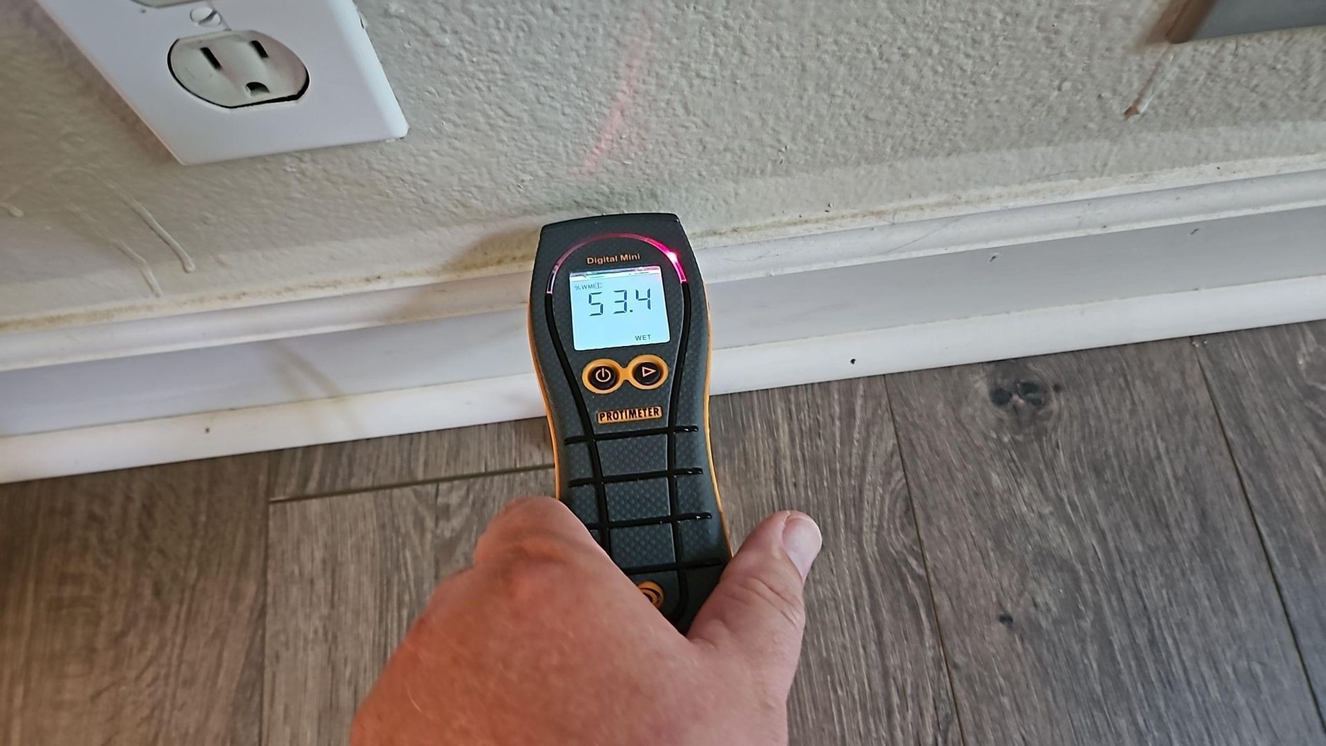 Moisture meter reading on bedroom drywall during water damage assessment