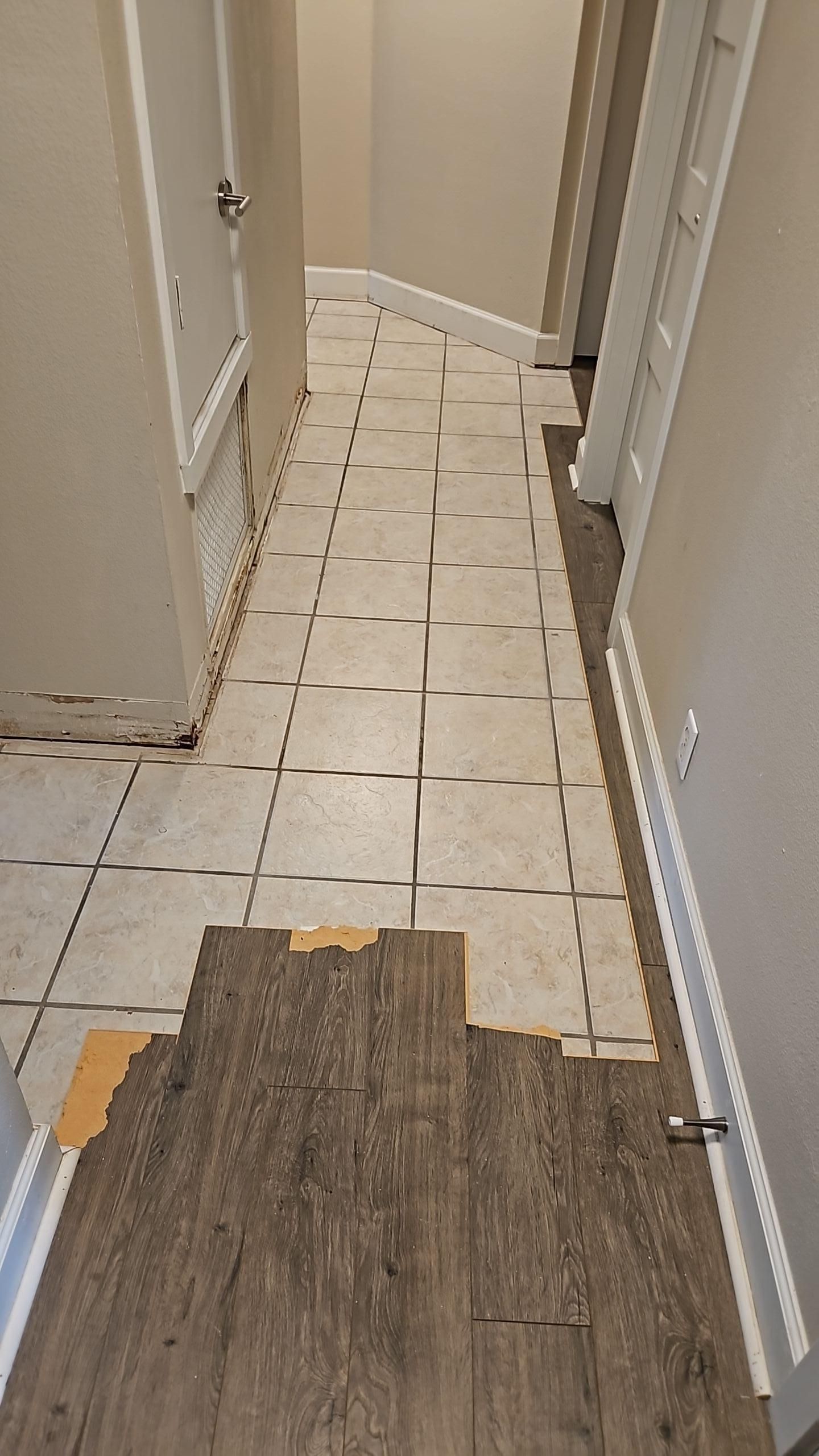 Hallway with laminate flooring removed exposing tile during water damage cleanup