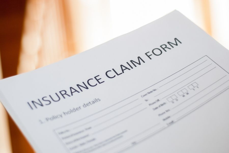 Homeowner filling out an insurance claim form after storm damage to their property