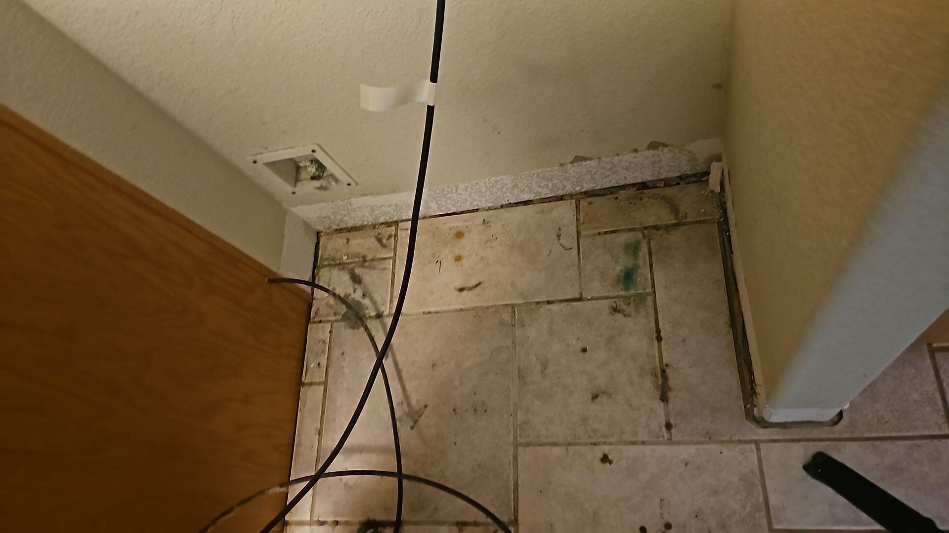 Water-damaged kitchen showing opened cabinet doors and moisture visible along the floor perimeter