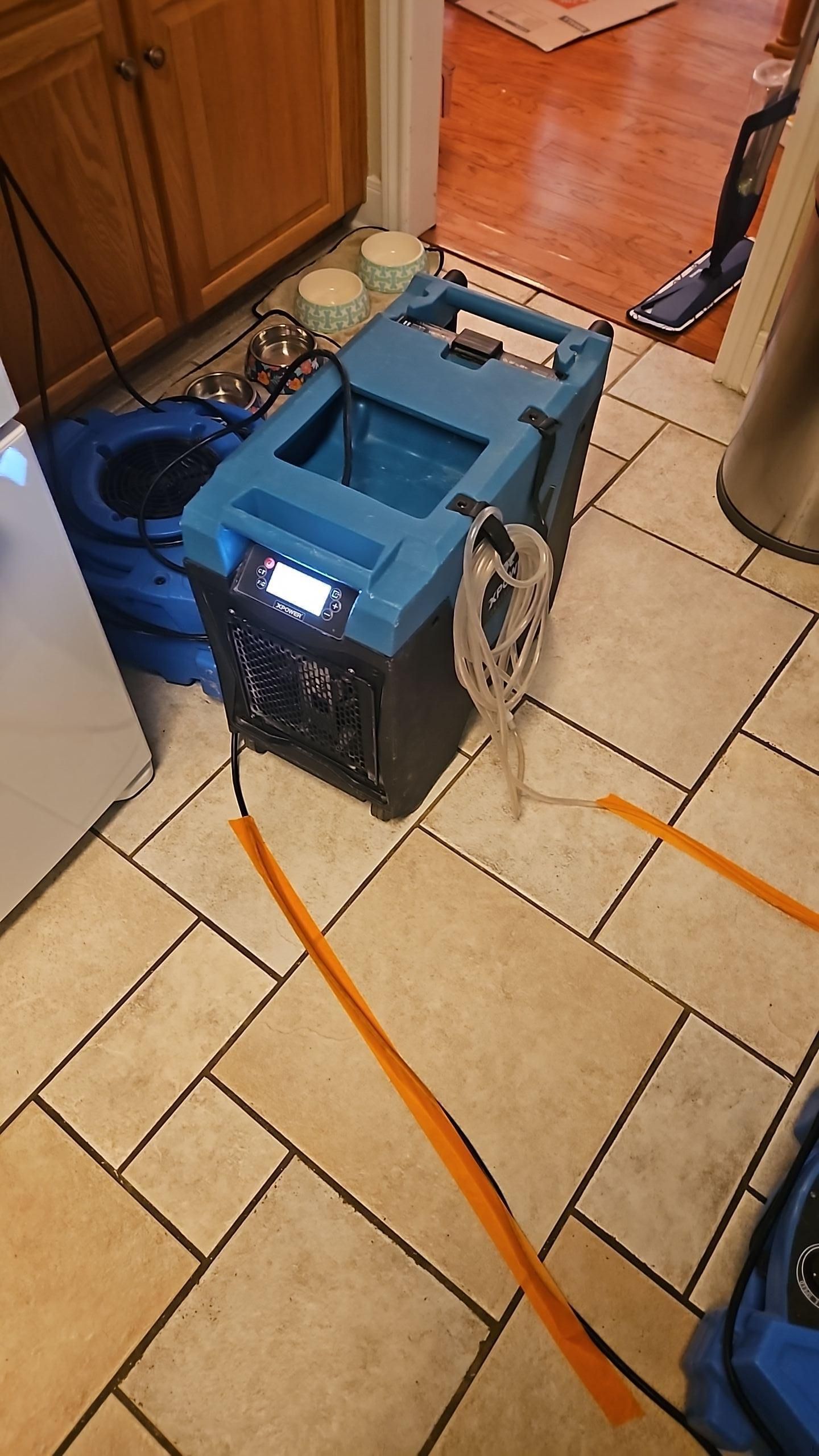 Close-up of drying equipment running along kitchen floor after water filtration system leak