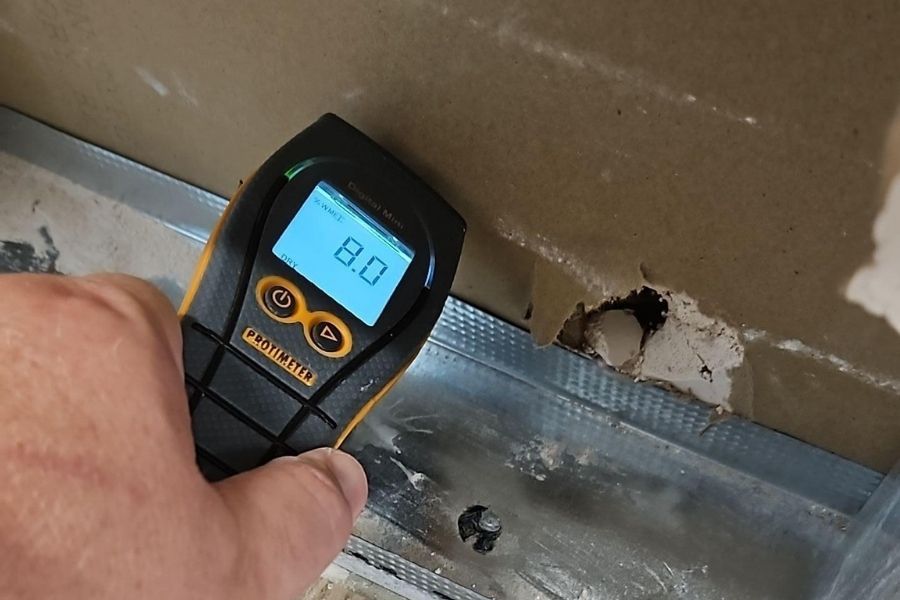 Restoration technician using a moisture meter to check moisture levels in a wall after flood damage