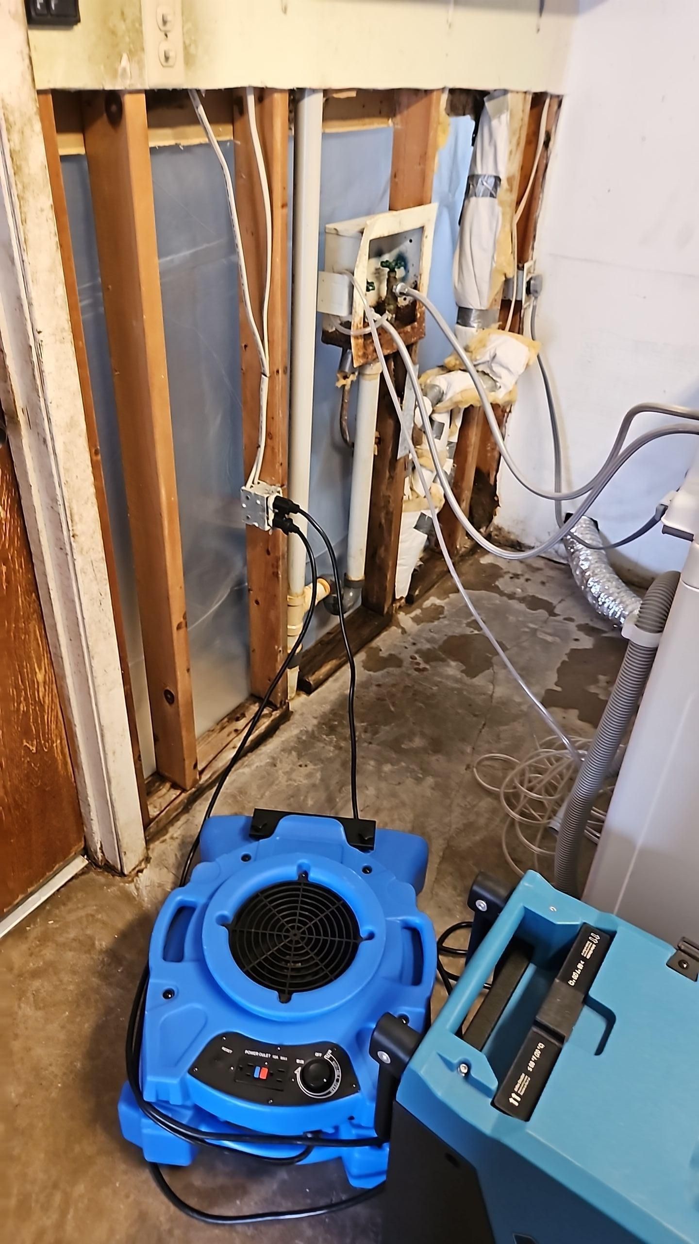 Air mover and dehumidifier placed in garage for structural drying after pipe leak