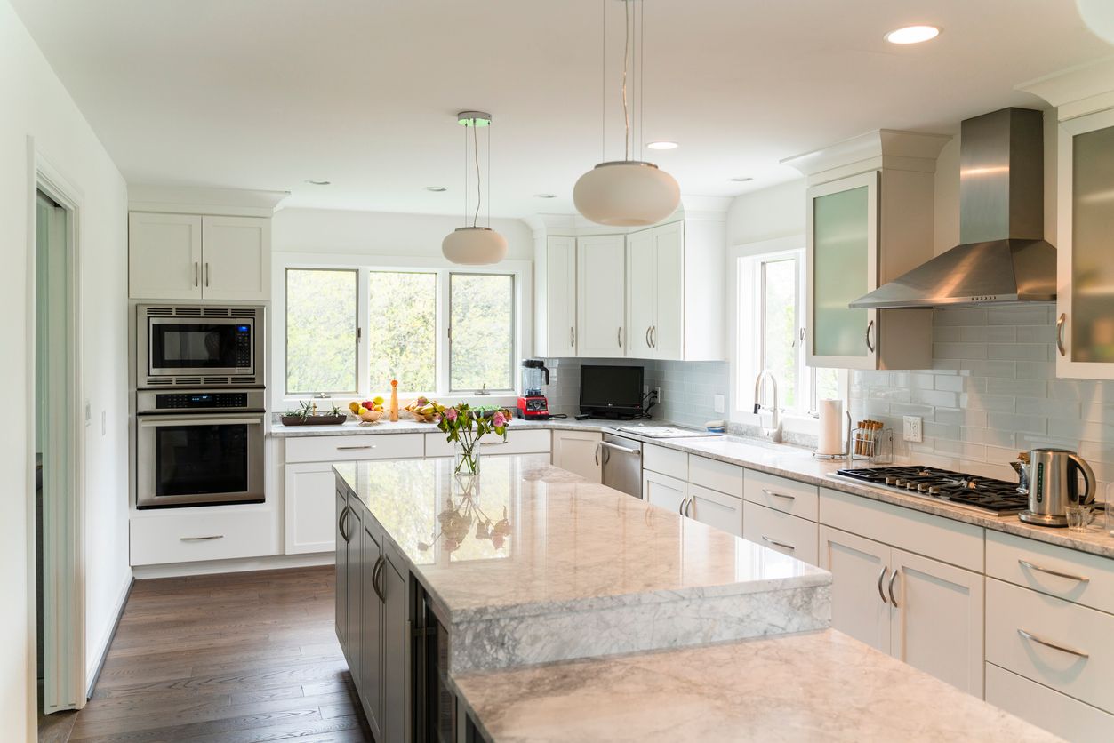 Bright modern kitchen with white cabinets, granite island, and stainless steel appliances