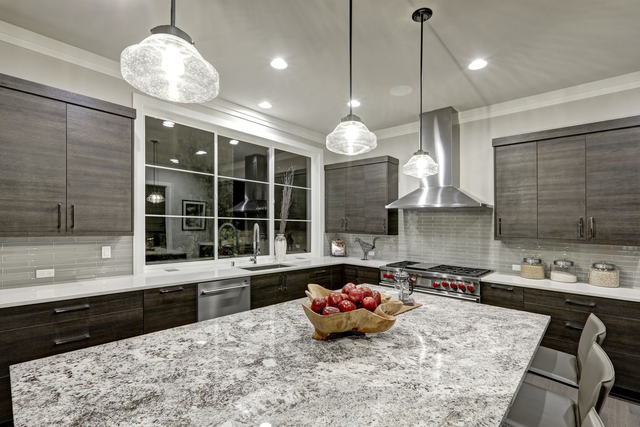 Modern kitchen with granite island, pendant lights, and a fruit bowl under a window
