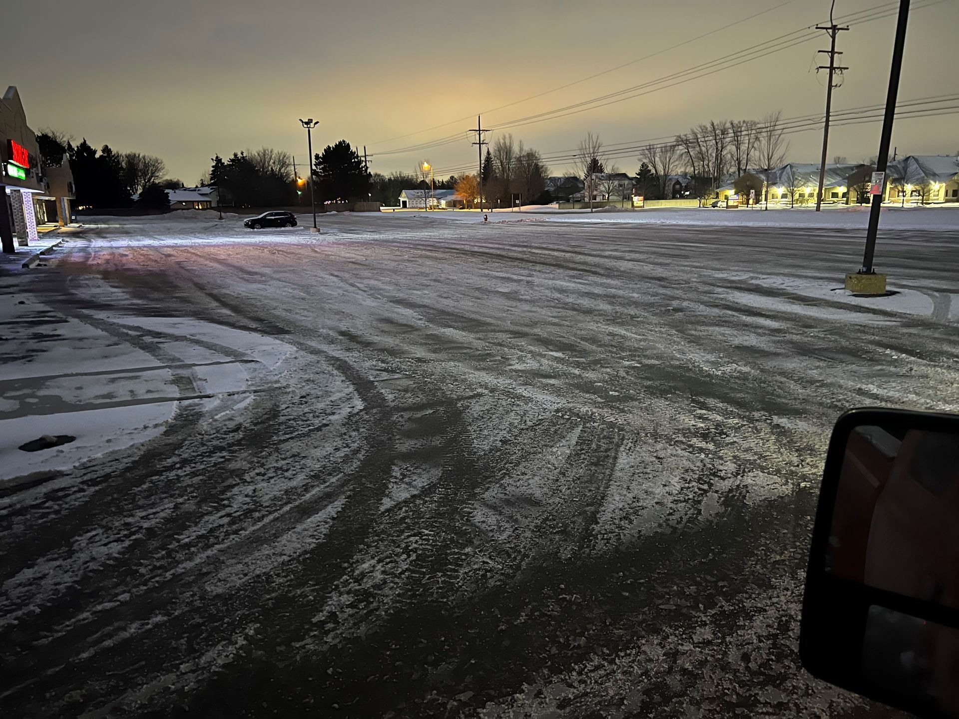 A car is driving down a snowy road at night.