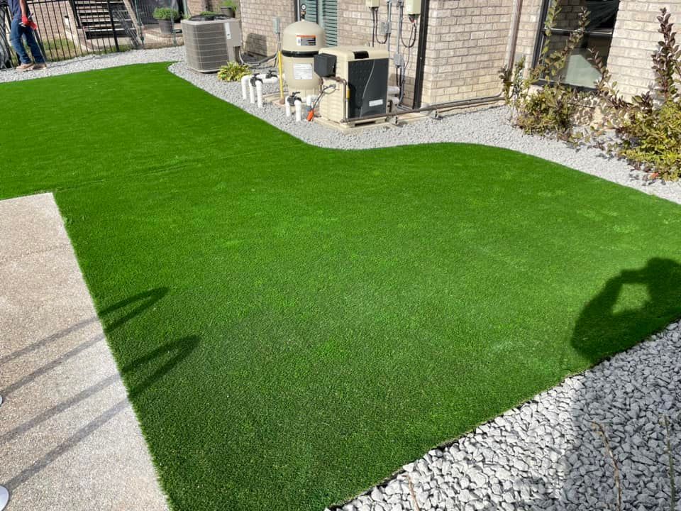 A backyard with a lush green lawn and a brick house in the background.