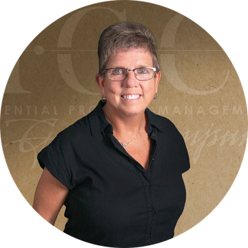 Woman wearing glasses and a black shirt, against a brown background.