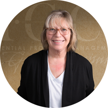 Woman with glasses smiling, wearing black cardigan over white shirt, background with logo.