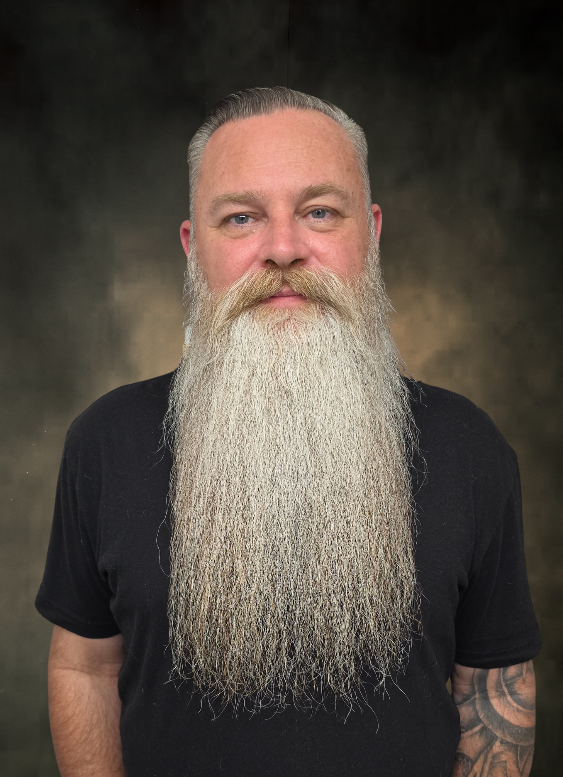 Portrait of a bearded man in a black shirt against a dark studio backdrop