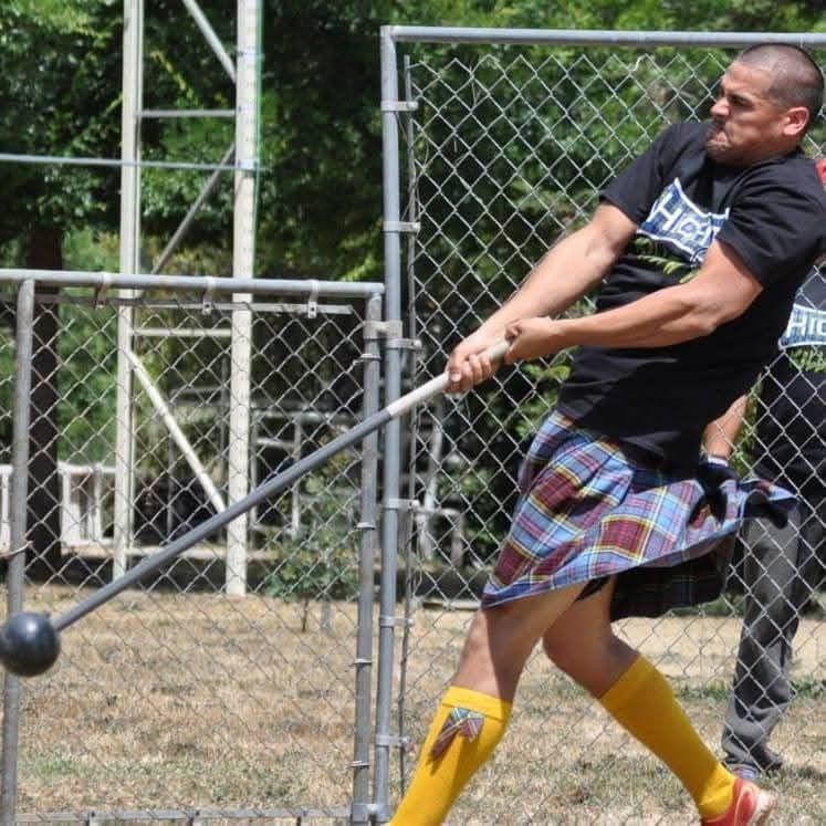 Man in kilt swings a heavy ball and chain, part of Highland games.