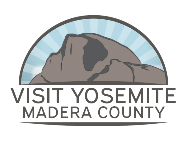 Logo for Visit Yosemite Madera County. Shows a gray mountain outline against a blue, sunburst sky. Text below.