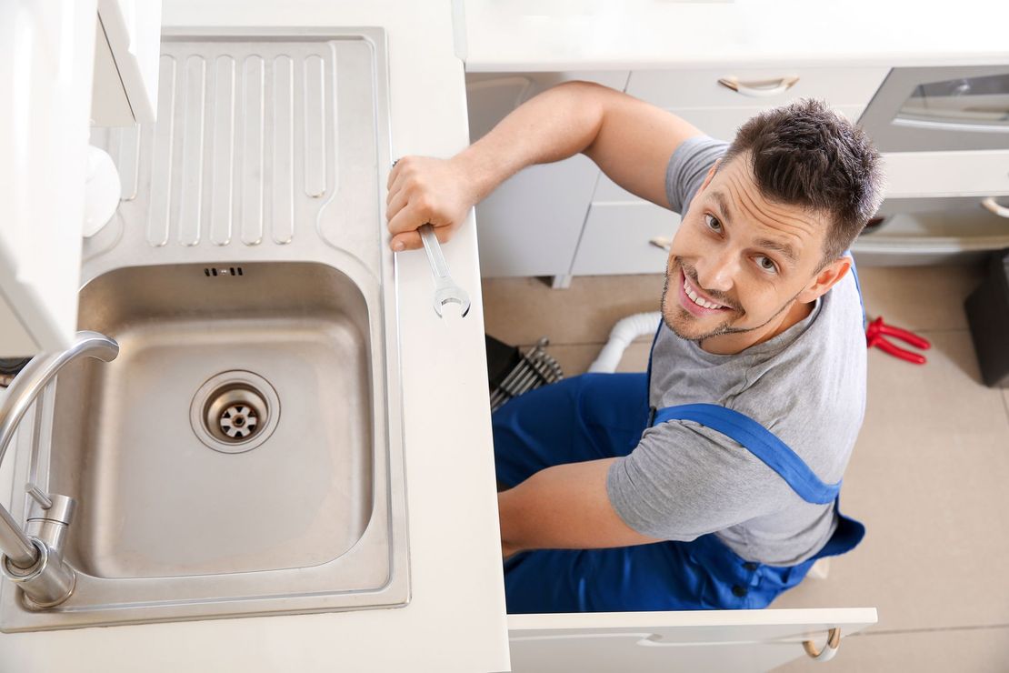 Plumber installing sink in kitchen