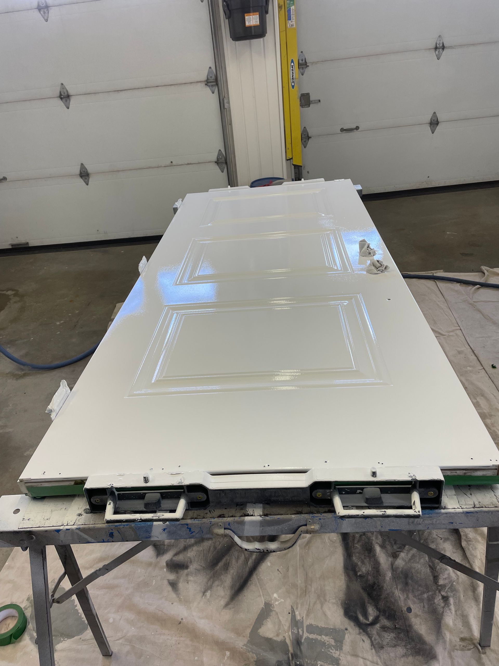 Une porte blanche est posée sur une table devant une porte de garage