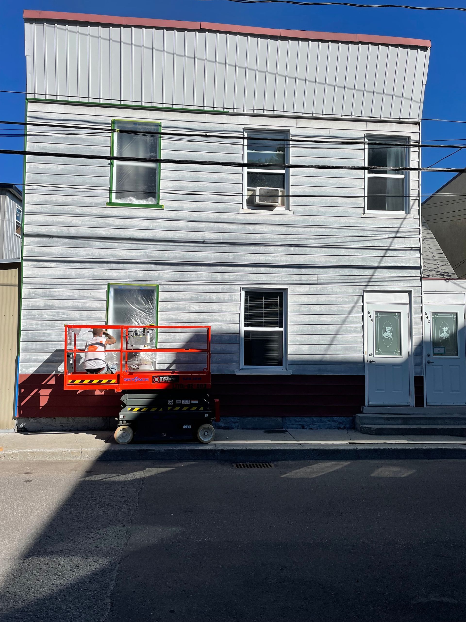 Un bâtiment blanc avec une bordure rouge est en train d'être peint