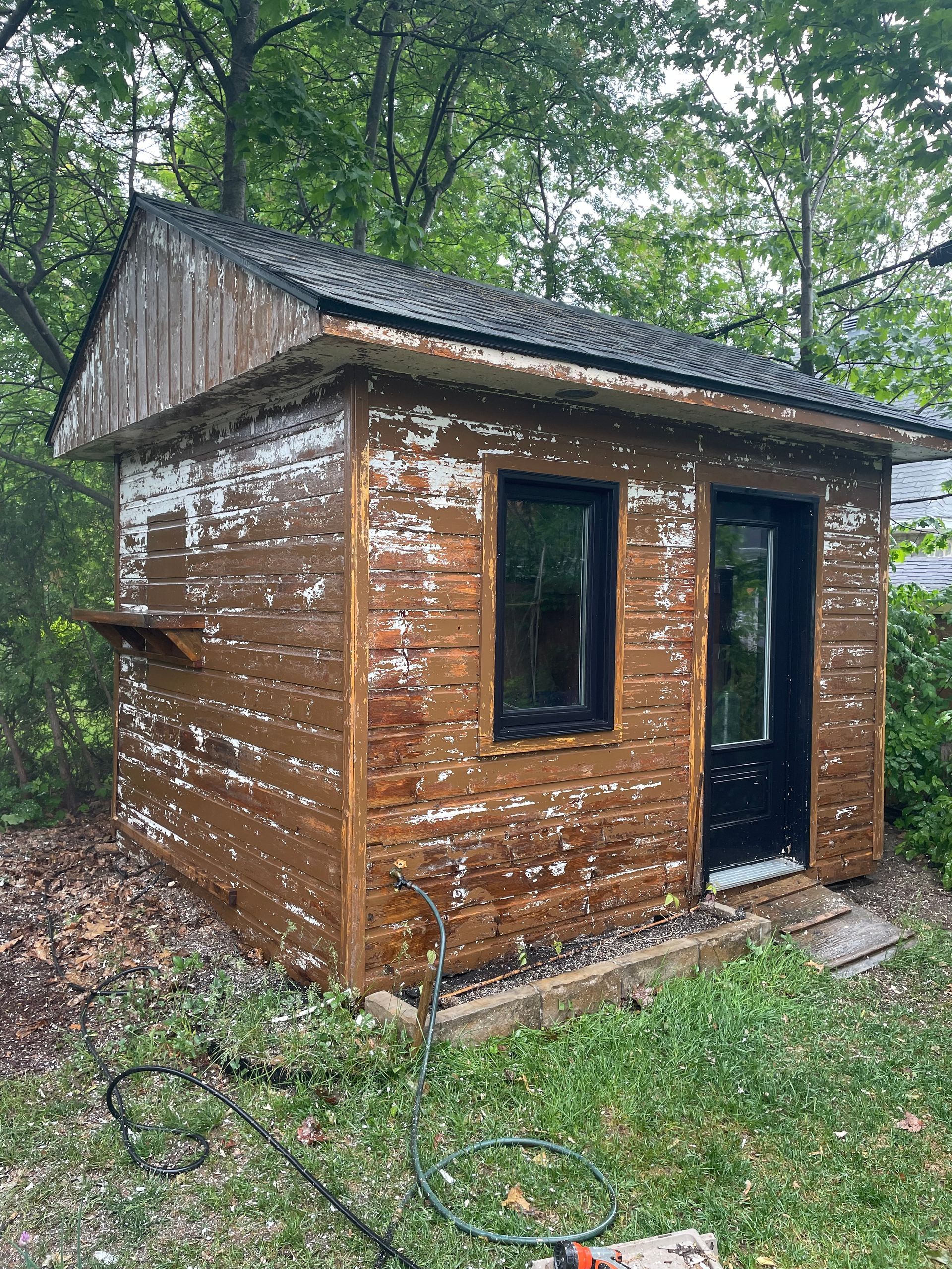 Un petit hangar en bois se trouve au milieu d'une cour.