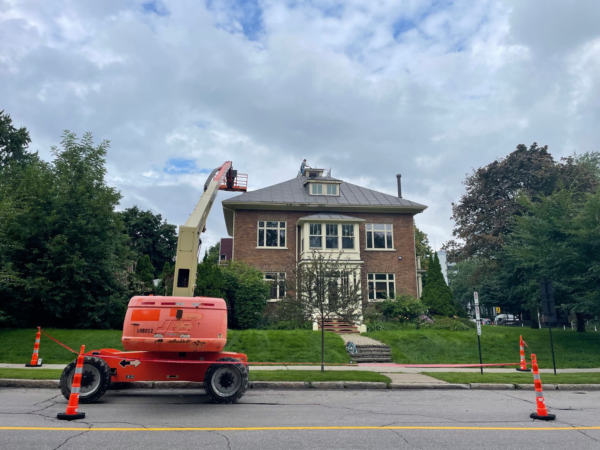 Un véhicule de chantier est garé devant une grande maison en brique.