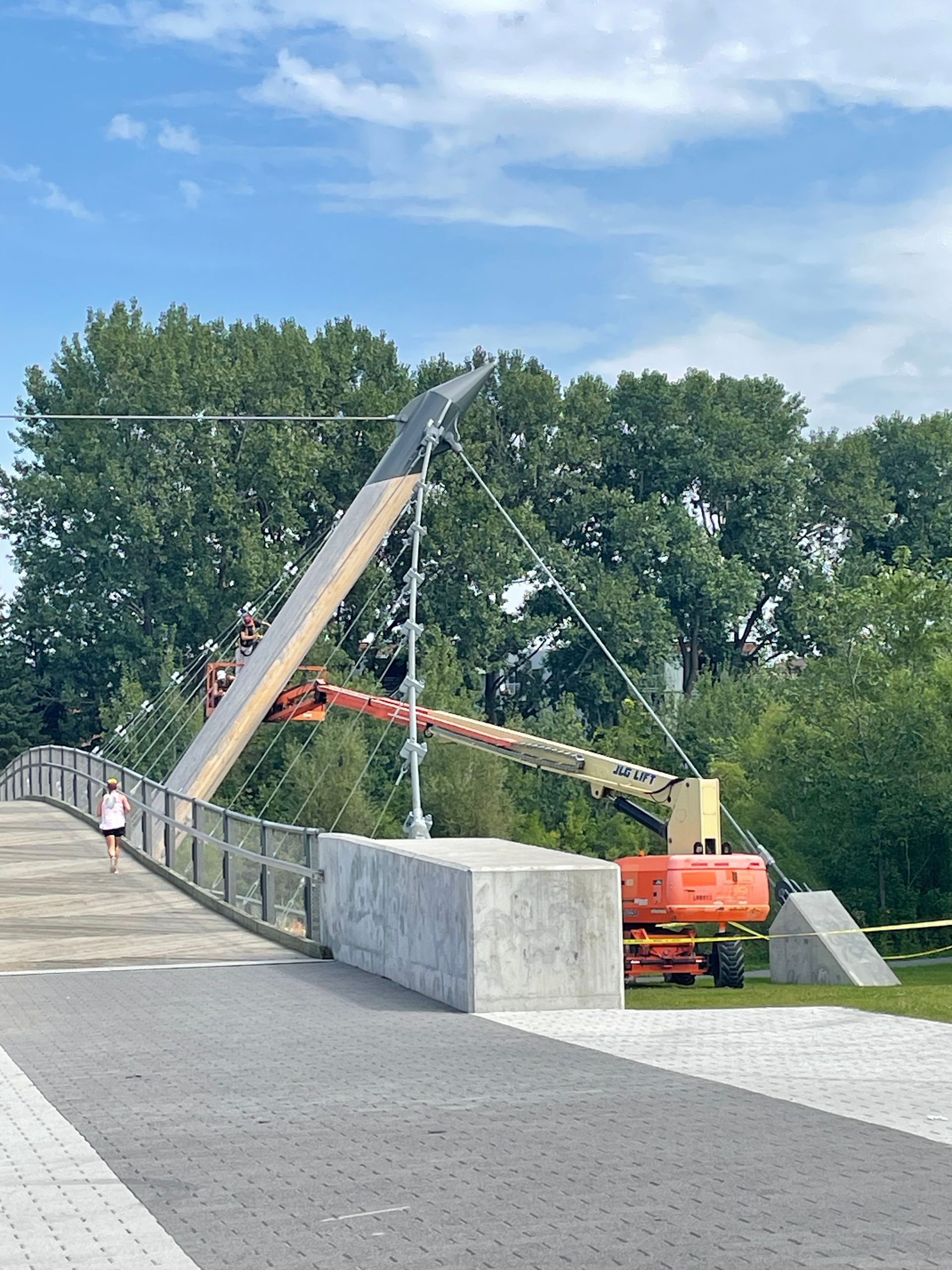 Une personne traverse un pont avec une grue en arrière-plan.