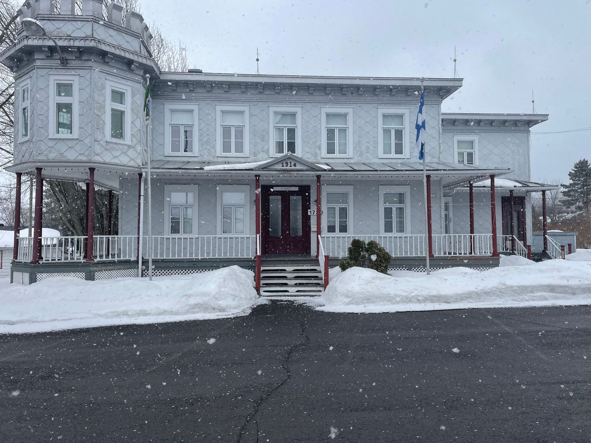 Une grande maison blanche avec de la neige au sol devant elle