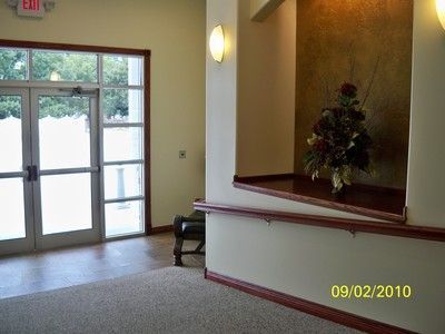 The front door of a house with a porch and plants in front of it.