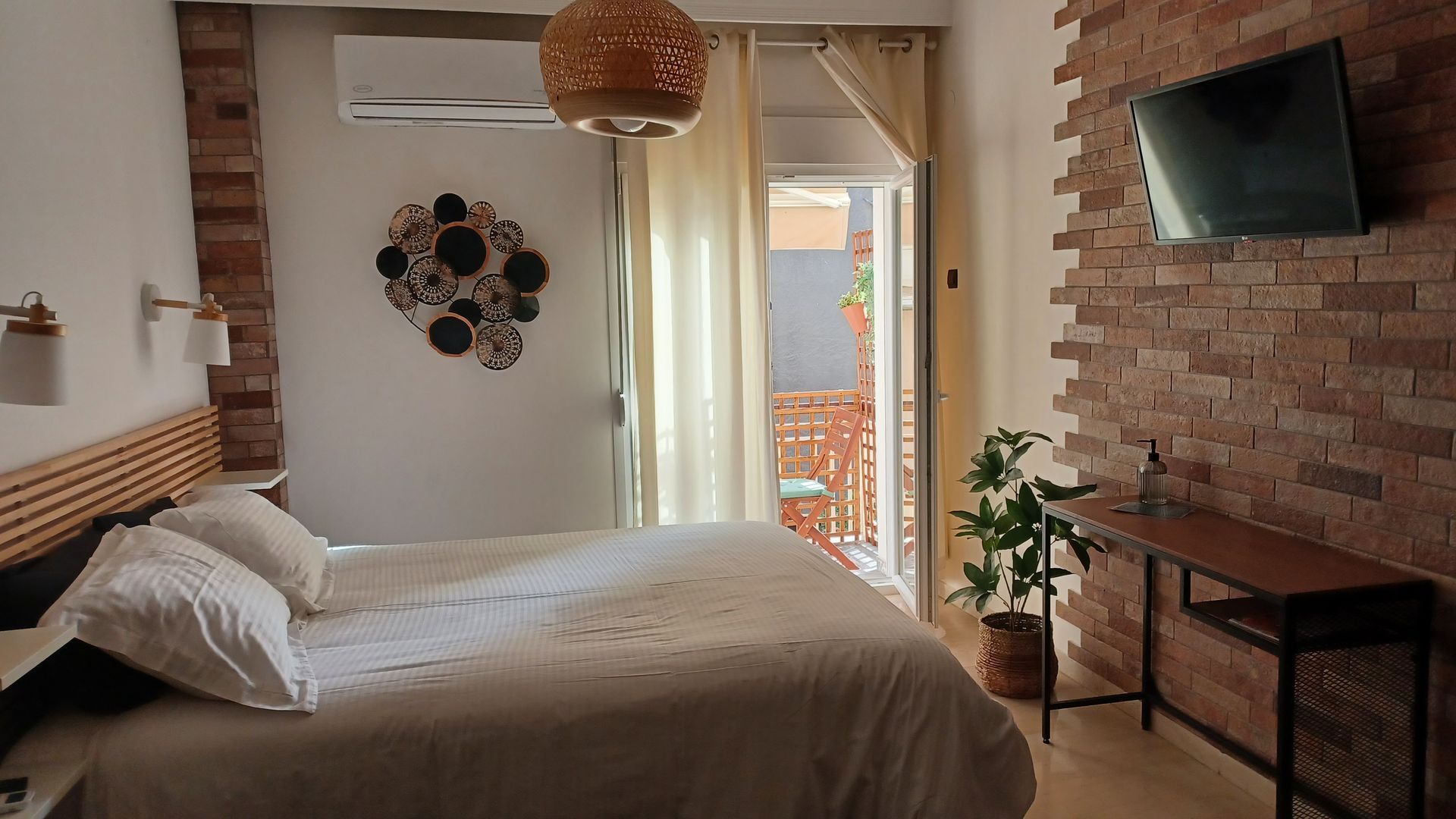 Υπνοδωμάτιο με τοίχους από τούβλα, πρόσβαση στο μπαλκόνι και διακοσμητικά έργα τέχνης.