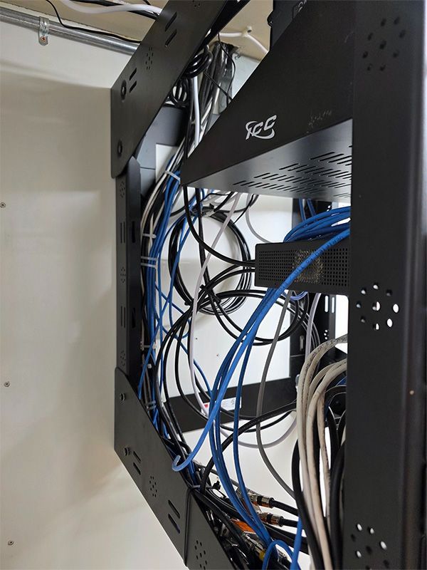Black server rack with tangled blue, white, and black cables inside a cabinet.