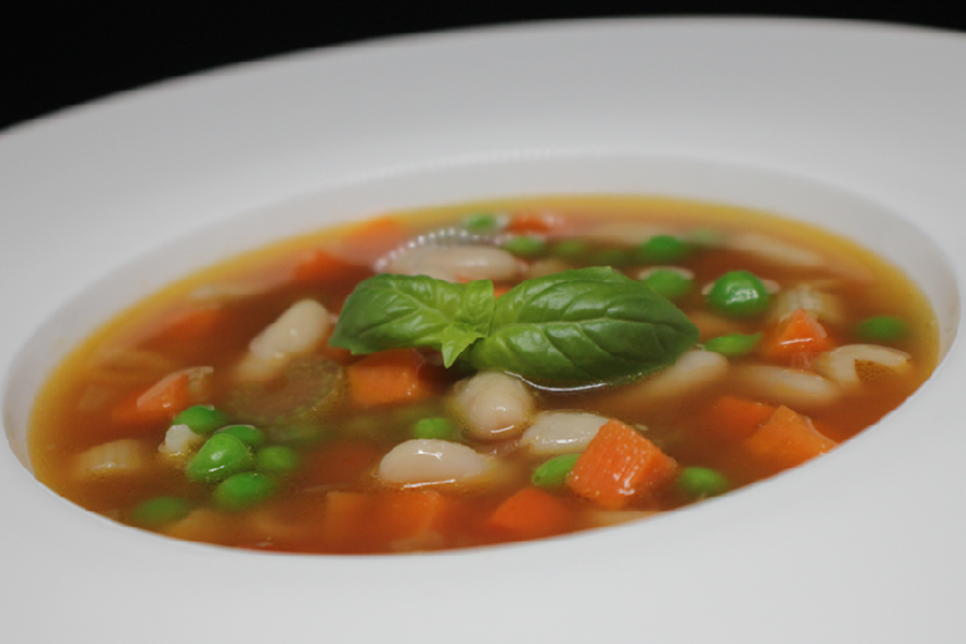 A bowl of hearty minestrone soup filled with a colorful mix of vegetables, beans, and pasta, in a rich tomato broth. A classic Italian comfort food
