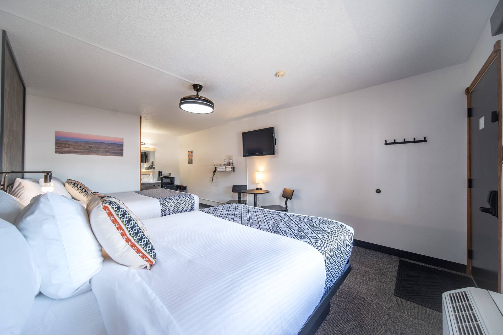 Bright hotel room with two beds, wall-mounted TV, and modern decor