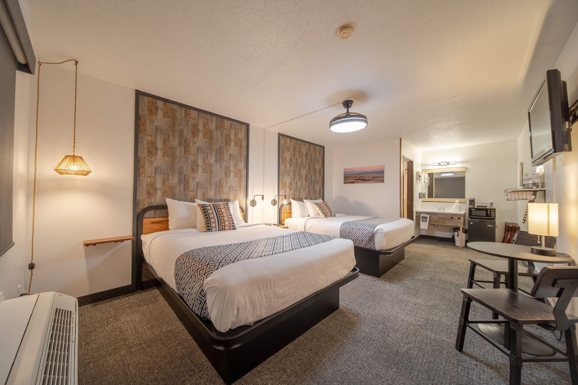 Cozy hotel room with two beds, lamp lighting, desk, and neutral decor