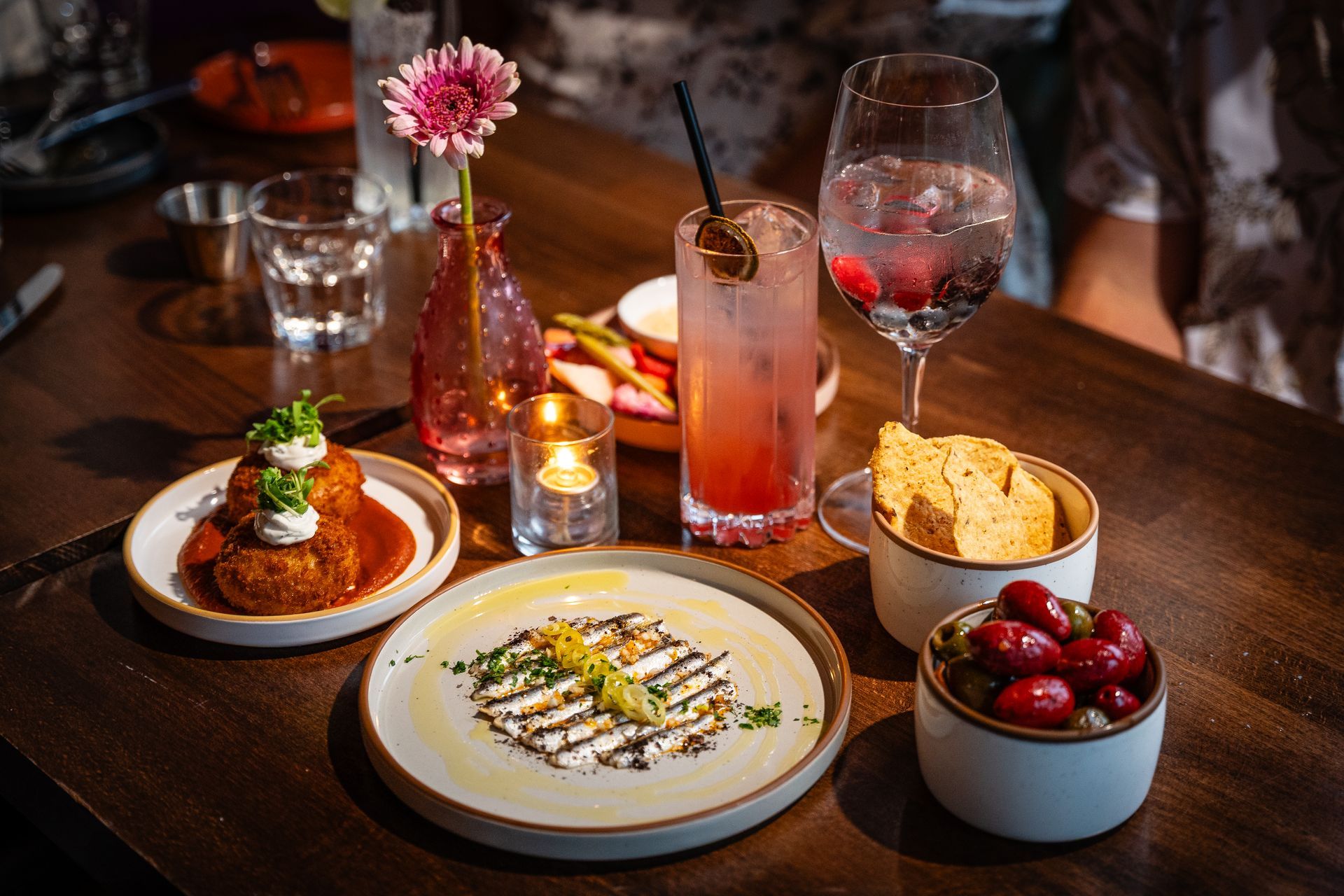 Dessert table with plated sweets, cocktails, and cherries in a dimly lit restaurant setting