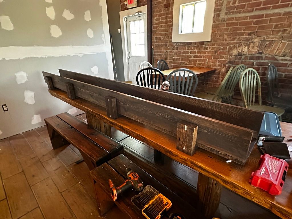 Long wooden church pews in a rustic room with brick walls and tiled floor
