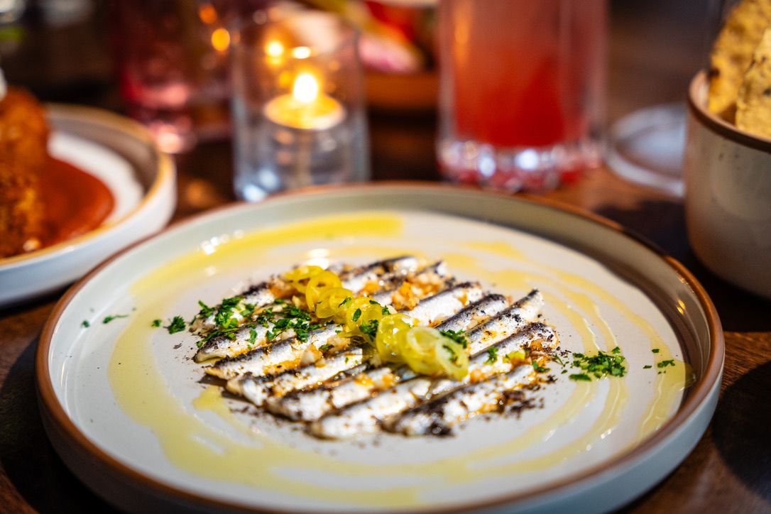 Creamy white dip topped with herbs and lemon, drizzled with oil on a restaurant table