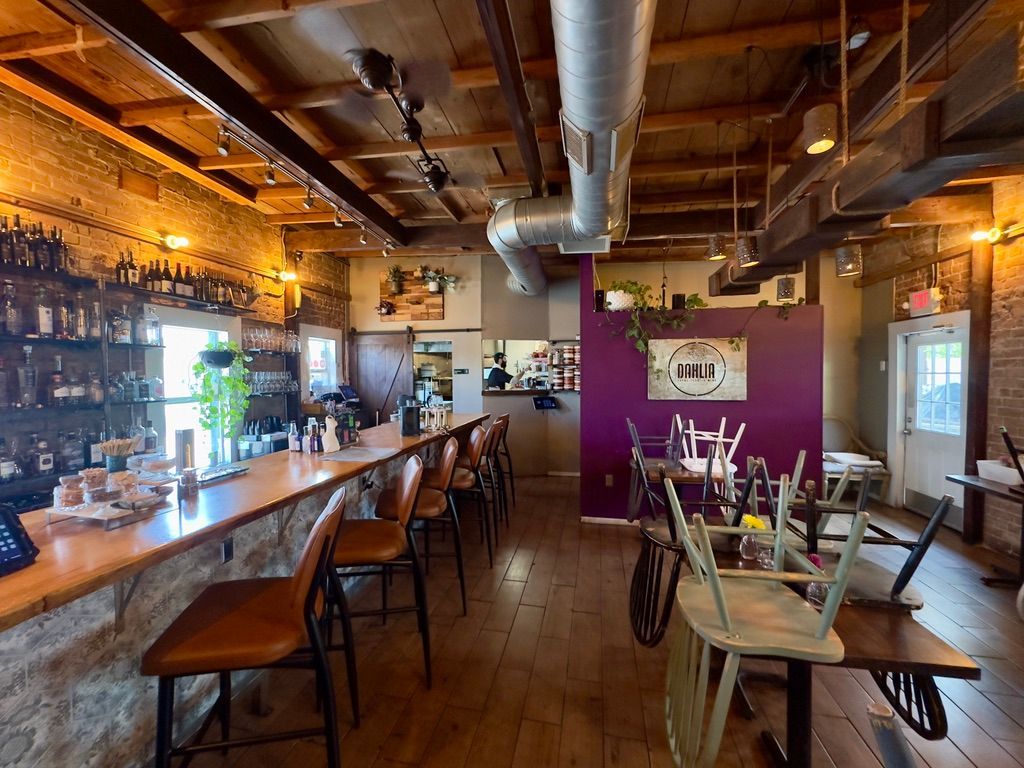 Empty rustic café interior with wooden tables, bar stools, and warm pendant lighting