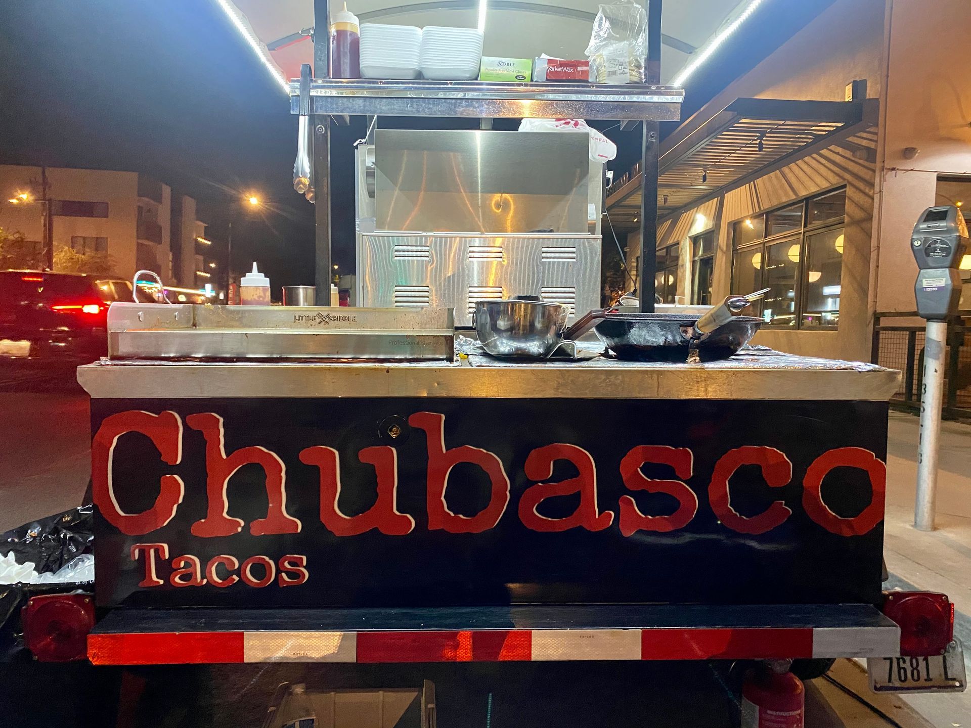 Chubasco Tacos food cart at night with lit counter and red logo sign