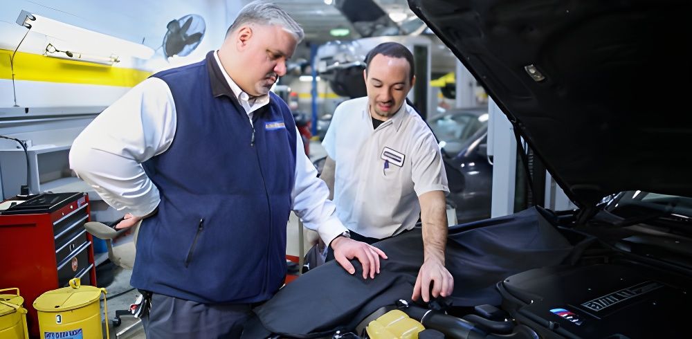 Two men are looking under the hood of a car | Excluservice