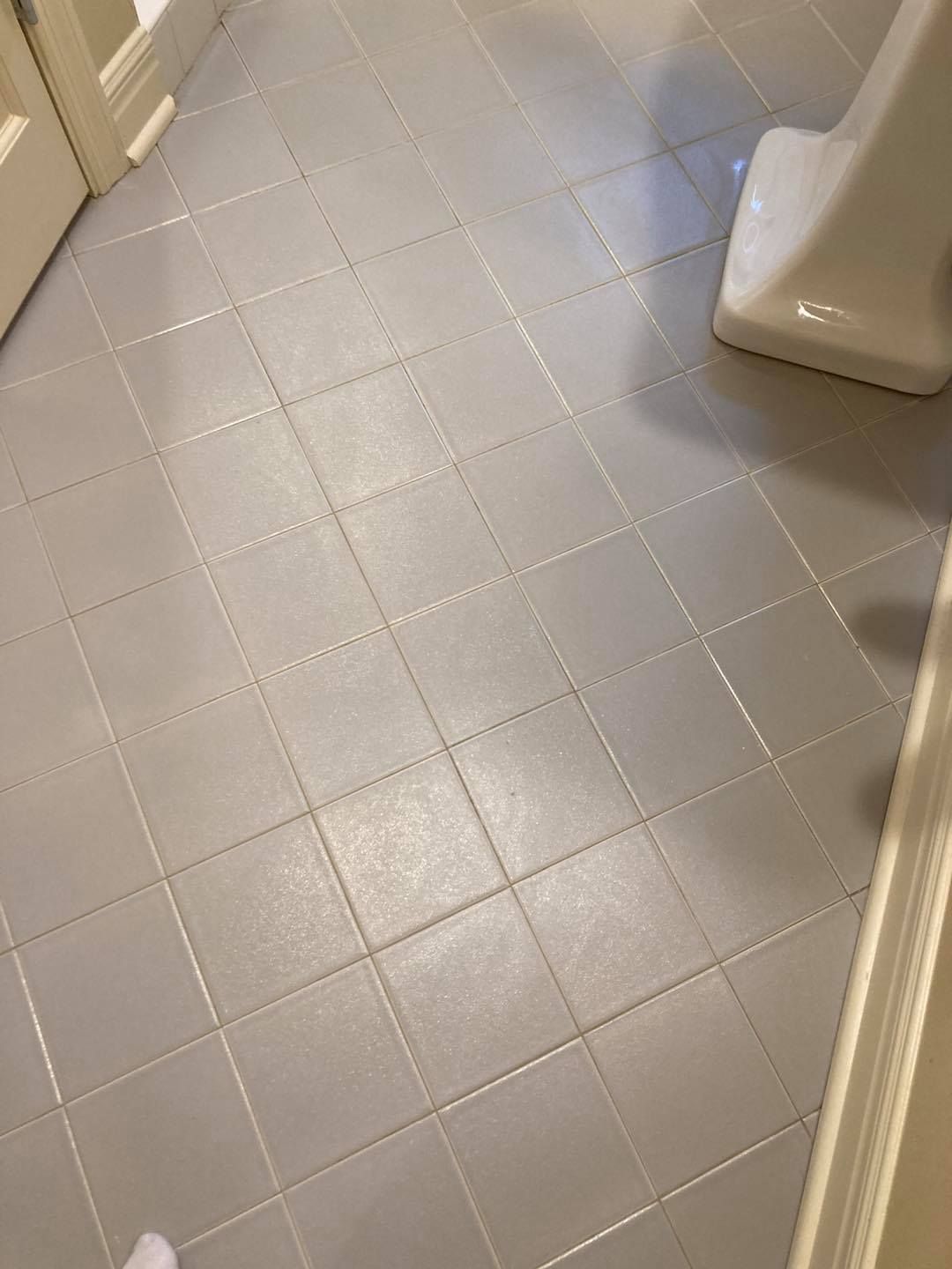 Bathroom floor with gray square tiles and part of a white fixture visible.