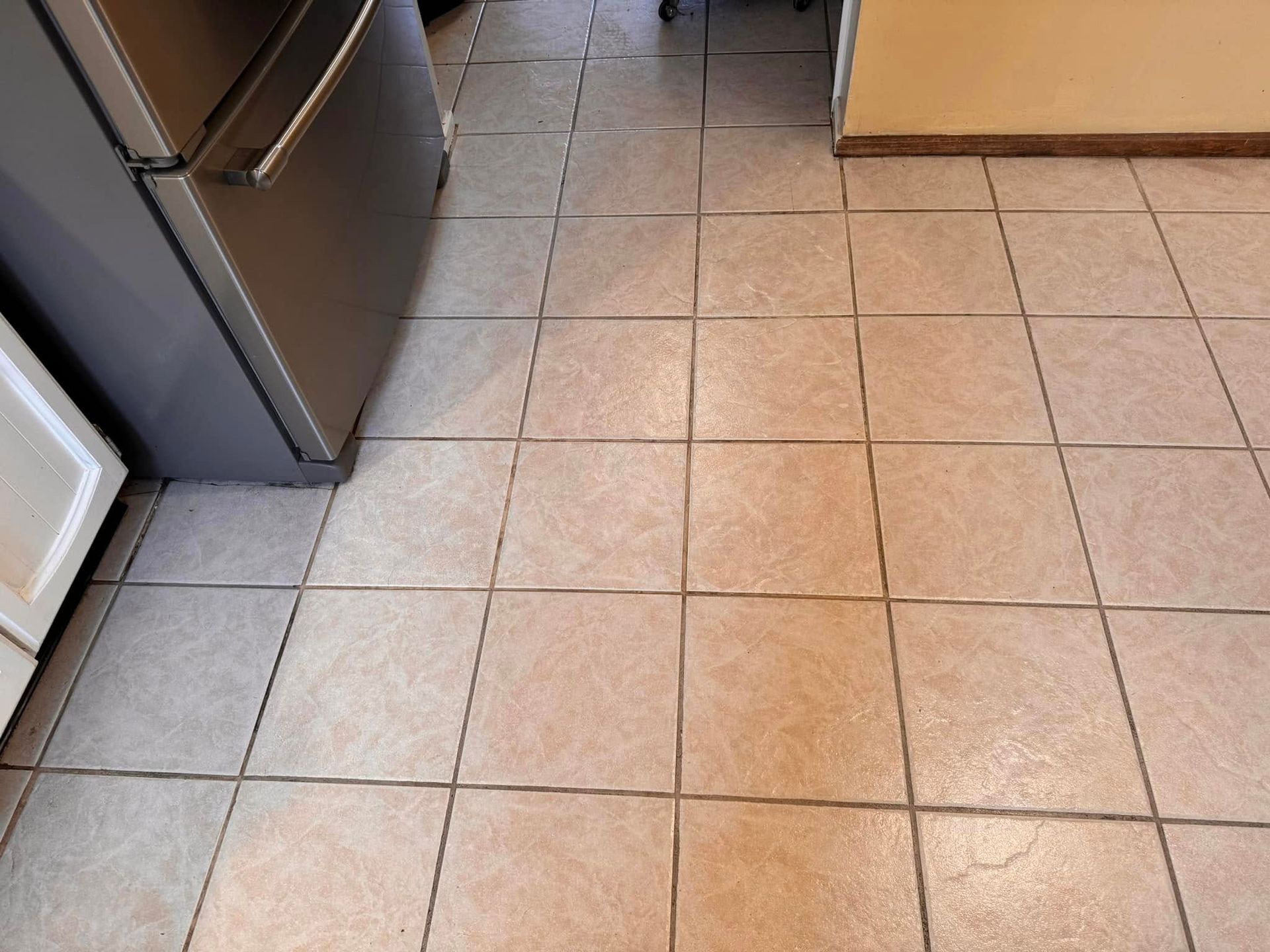 Kitchen floor with beige tile, stainless steel appliance on the left, and a cabinet at the top right