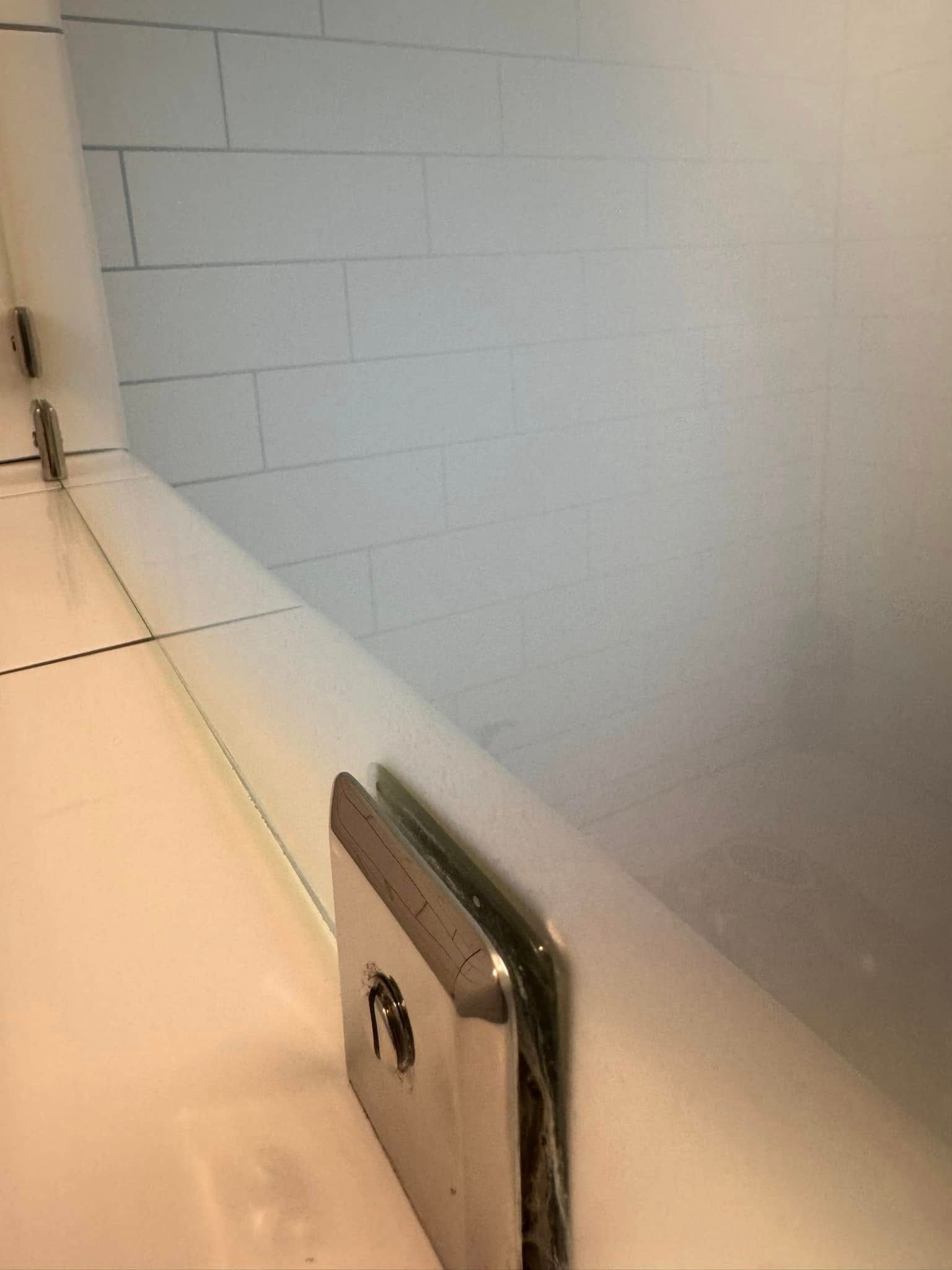 White tiled shower corner with a built-in soap dish and a small metal fixture on the ledge.