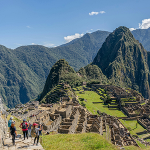 Tourists hiking above the stone terraces of Machu Picchu with green mountains in the background