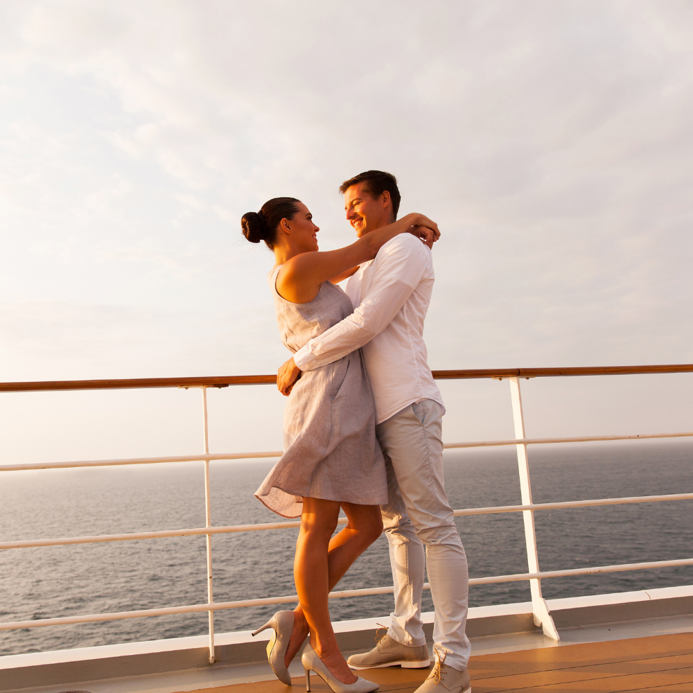 Couple embracing on a ship deck at sunset with the ocean in the background